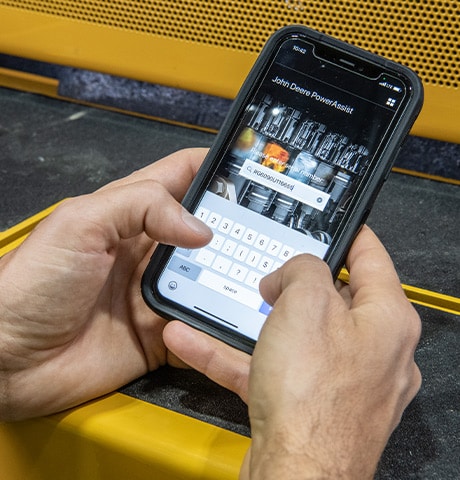 Mains qui entrent du texte sur un téléphone pour enregistrer un moteur John Deere