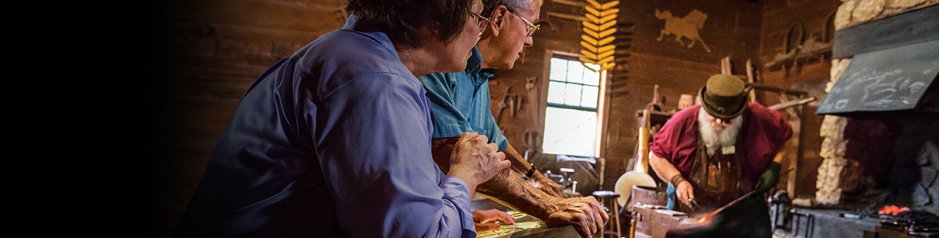 Couple âgé regardant le forgeron avec un marteau métallique sur un site historique à Grand Detour, Illinois, États-Unis