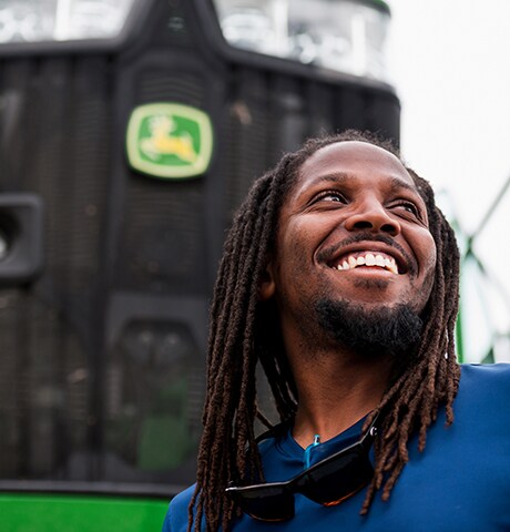 Un employé souriant se tient devant un tracteur