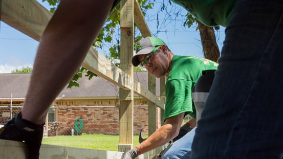 Deux personnes qui construisent une clôture ensemble près d’un bâtiment.