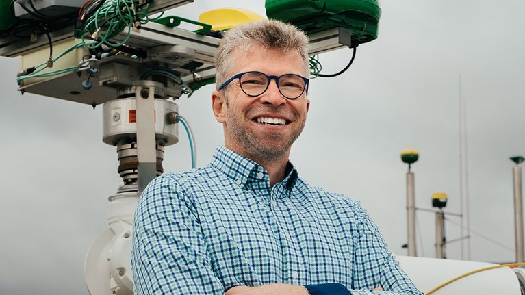 Georg Kormann devant un bras robotisé.