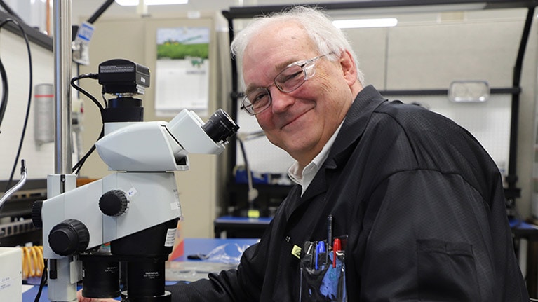 William F. Cooper assis devant un microscope