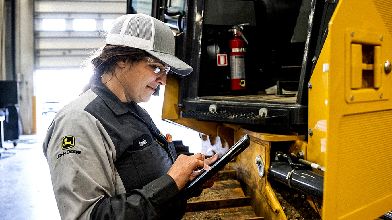 Technicien John Deere utilisant une tablette devant un équipement