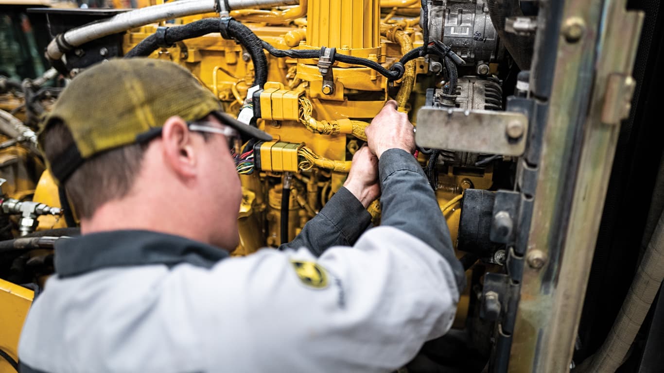 Homme portant des lunettes de sécurité pendant une intervention sur un moteur John Deere