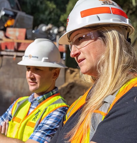 Ouvriers et ouvrières portant des casques de chantier et des gilets de sécurité, et examinant un équipement de construction