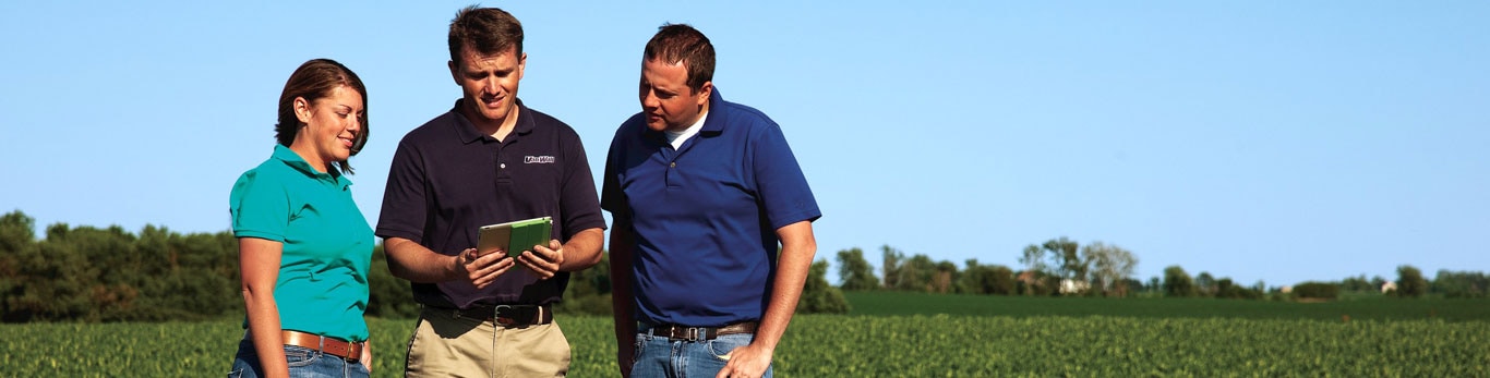 Three people talking in a farm field