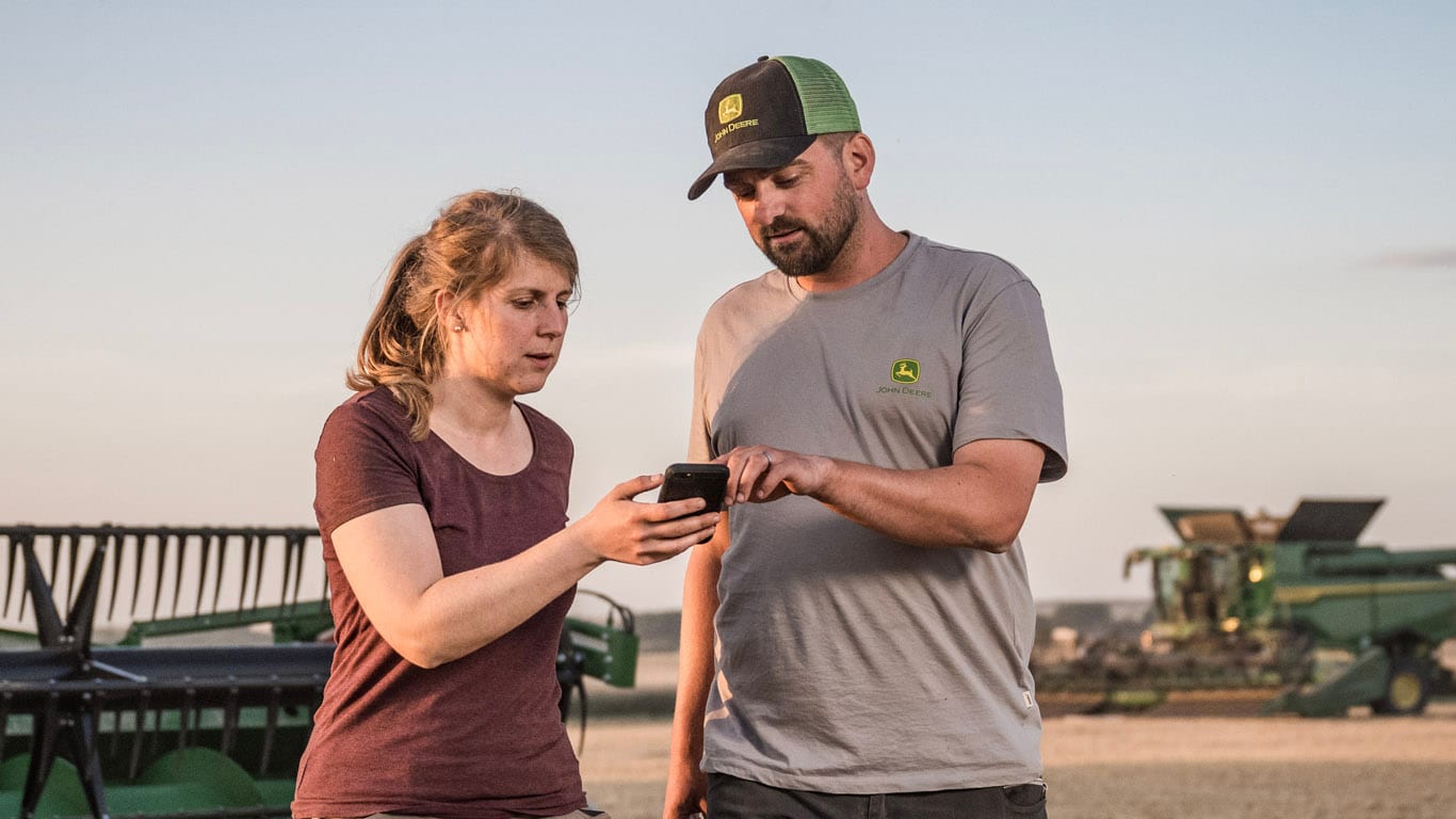 Deux personnes à l’extérieur, l’une tenant un smartphone tandis que l’autre pointe vers l’écran