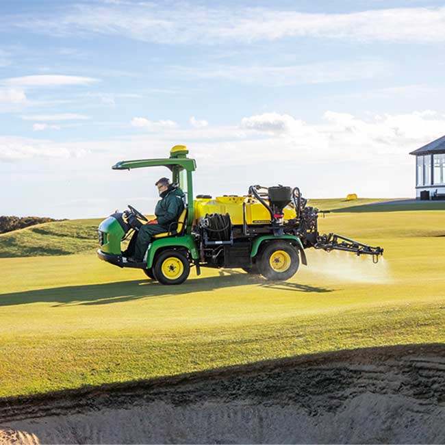 Greenkeeper travaillant sur un gazon avec un pulvérisateur John Deere