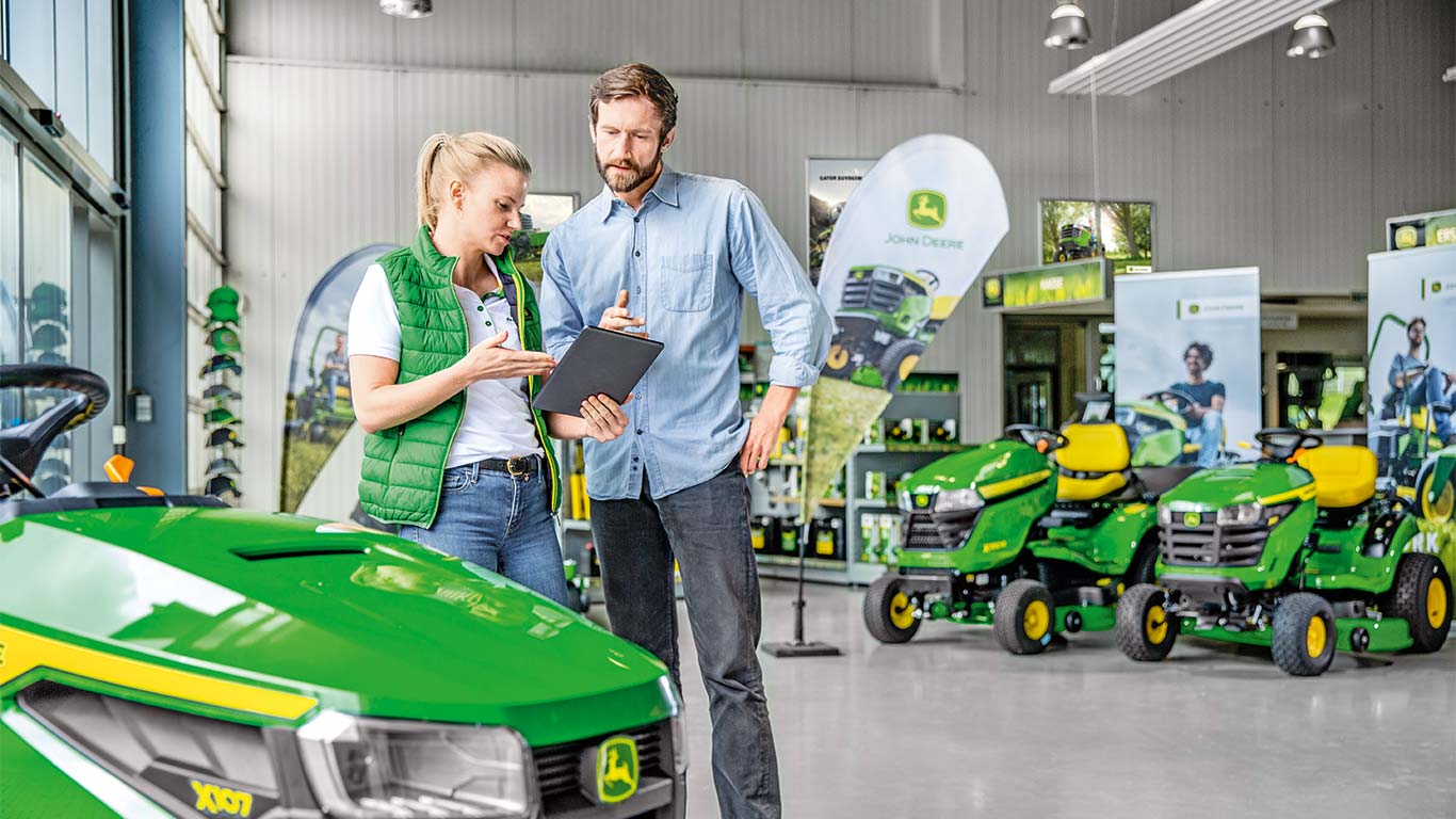 Concessionnaire John Deere conseillant un client sur l’achat d’une tondeuse John Deere.