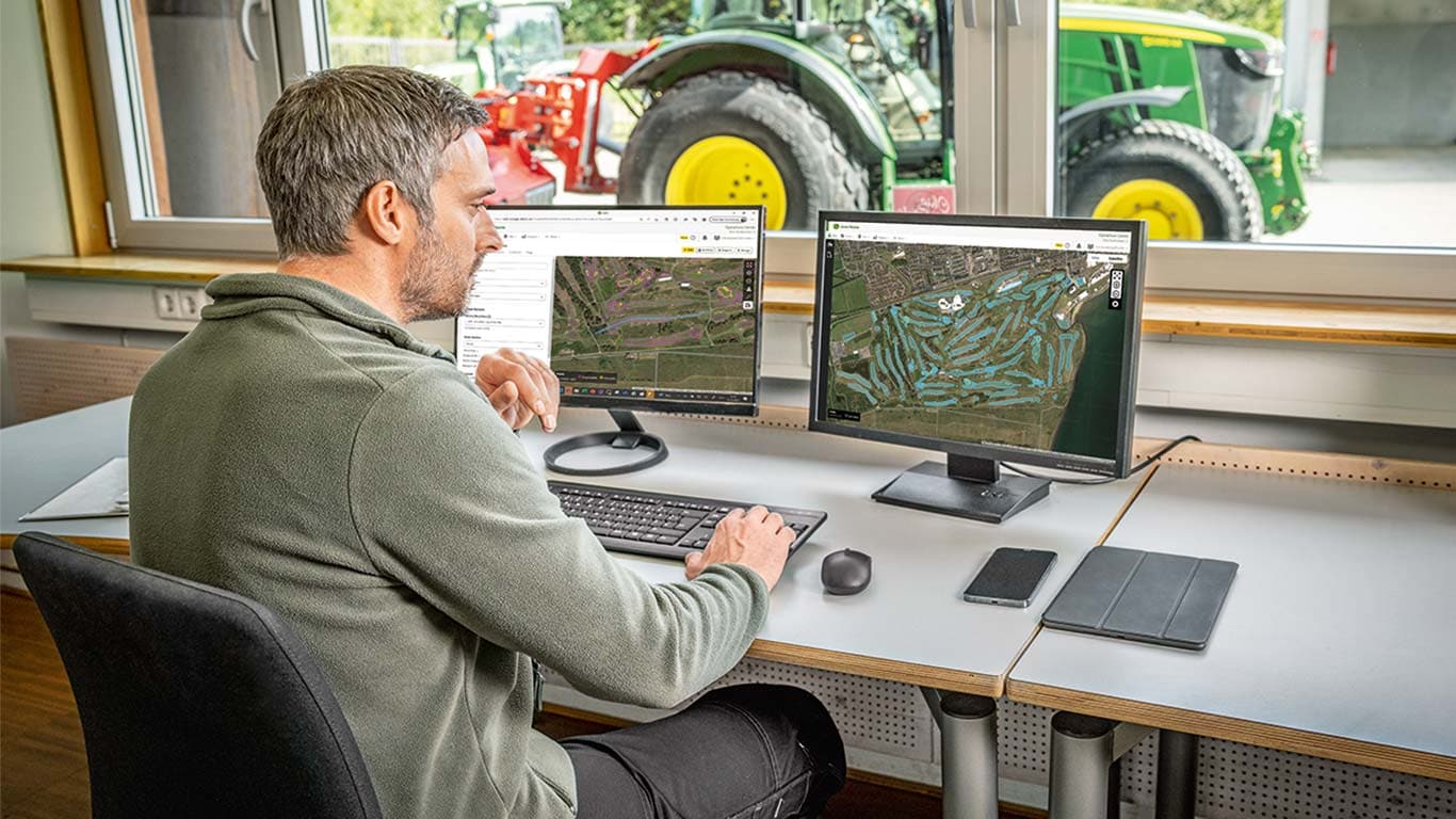 Un greenkeeper en chef consulte les cartes d’un terrain de golf sur son ordinateur.