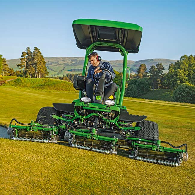 Vue de face d’un greenkeeper passant une tondeuse de greens John Deere.