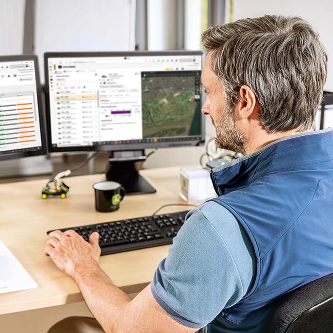 Greenkeeper en chef assis à son bureau, examinant les données collectées par les technologies intelligentes d’entretien des greens.