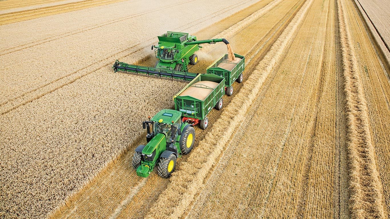 Moissonneuse-batteuse John Deere série S déchargeant du blé dans des remorques doubles tirées par un tracteur